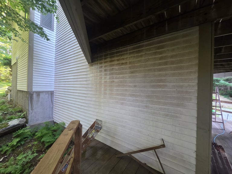 Covered patio area under a wooden structure with brick wall, ladder, and wood logs on the ground